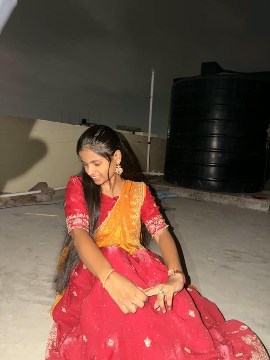 Bhargavi in a red and golden lehenga on a rooftop at night